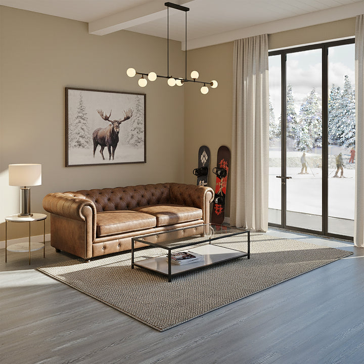Modern living room with brown leather sofa, gray LVP floors, glass coffee table, and large window showing snowy outdoor scene.