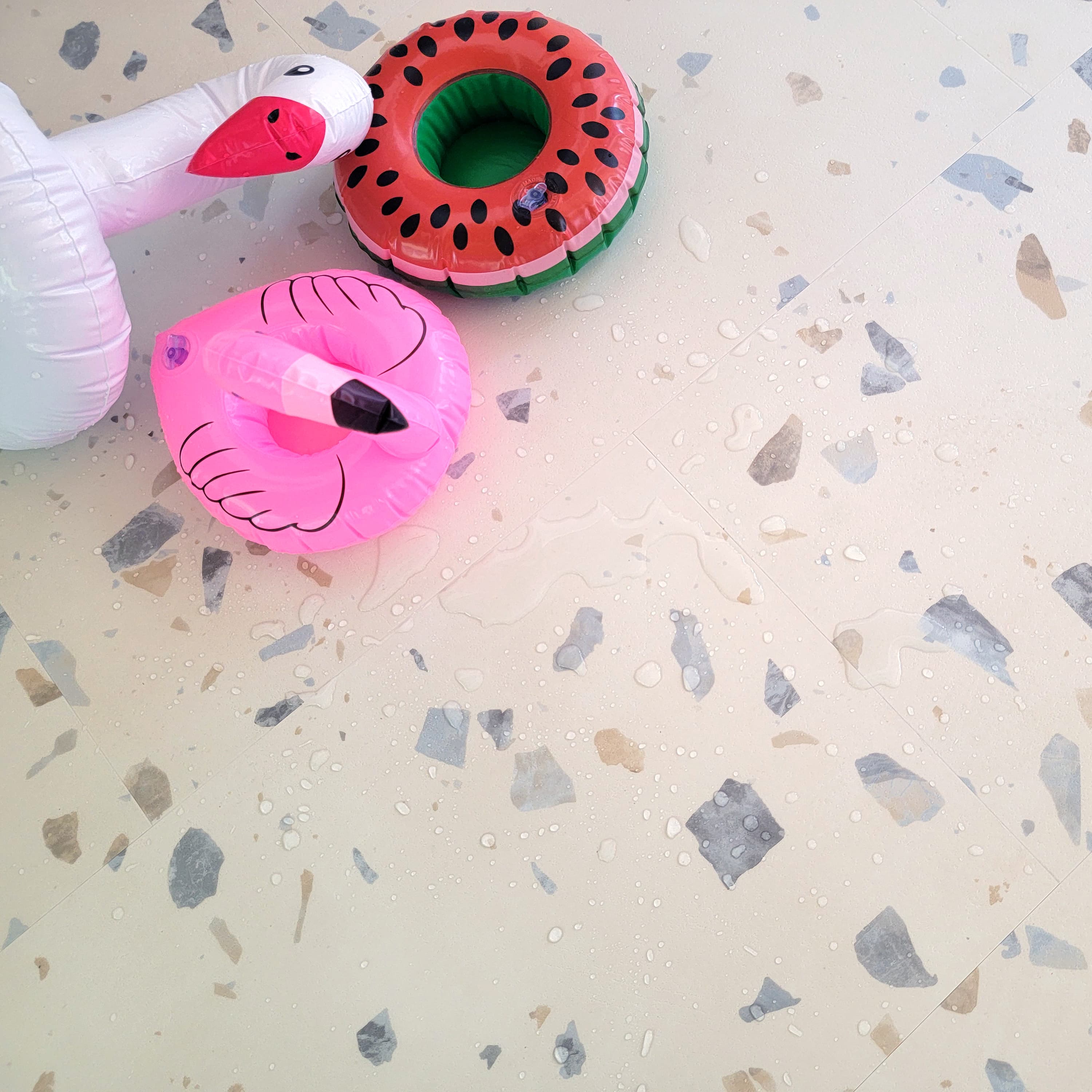 Close up of Allure terrazzo tile vinyl flooring with water on it and pool toys