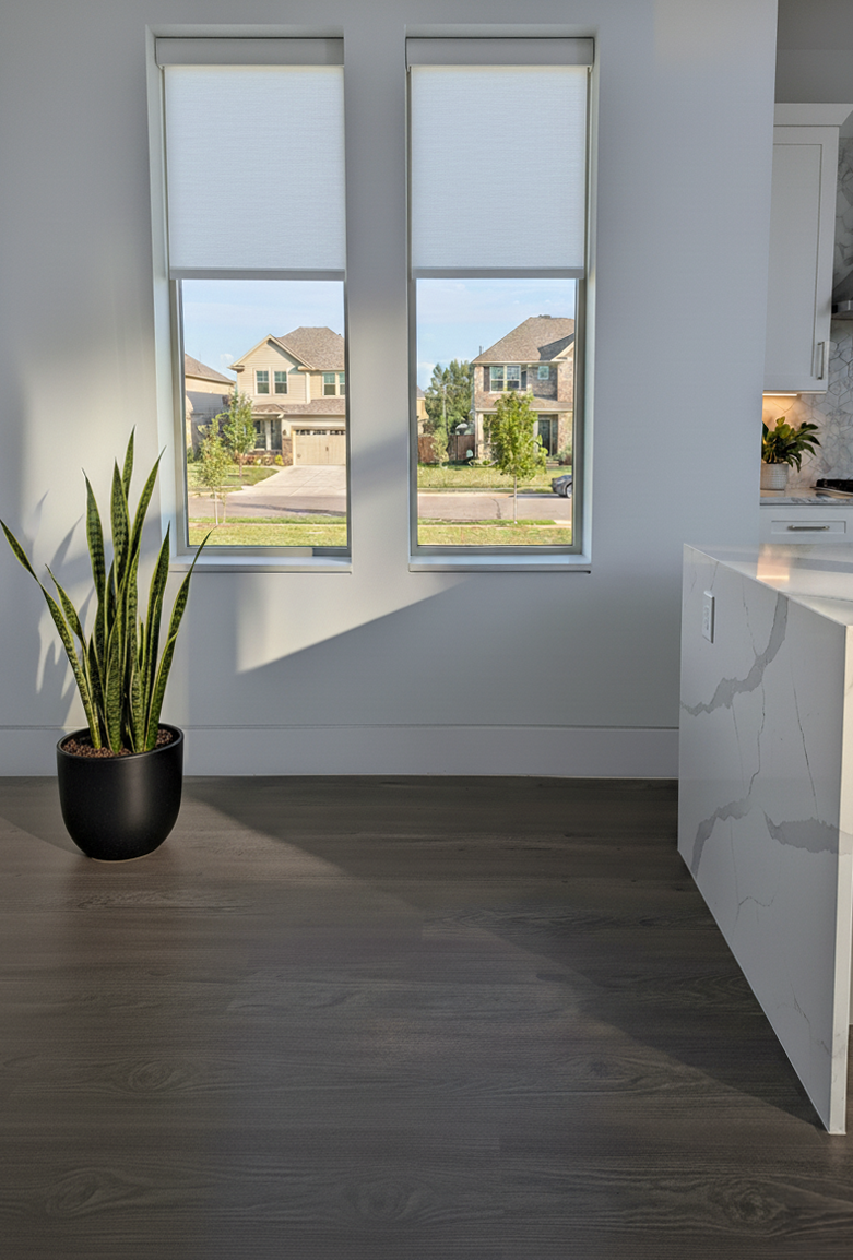 Modern interior with Allure LVP flooring, a plant, kitchen counter, and view of suburban houses through large windows.