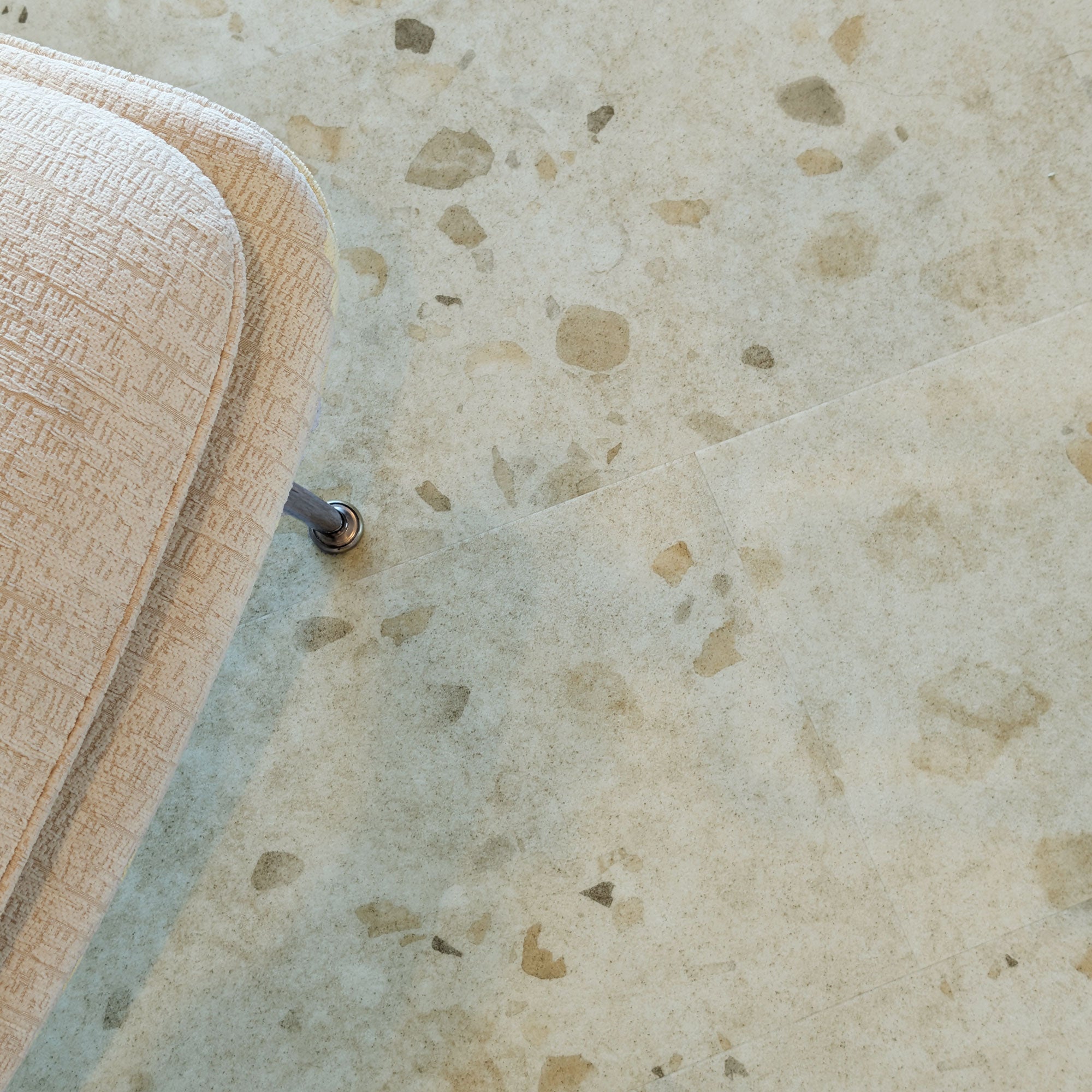 Close up of Allure Colada Concrete terrazzo flooring with edge of white chair in view