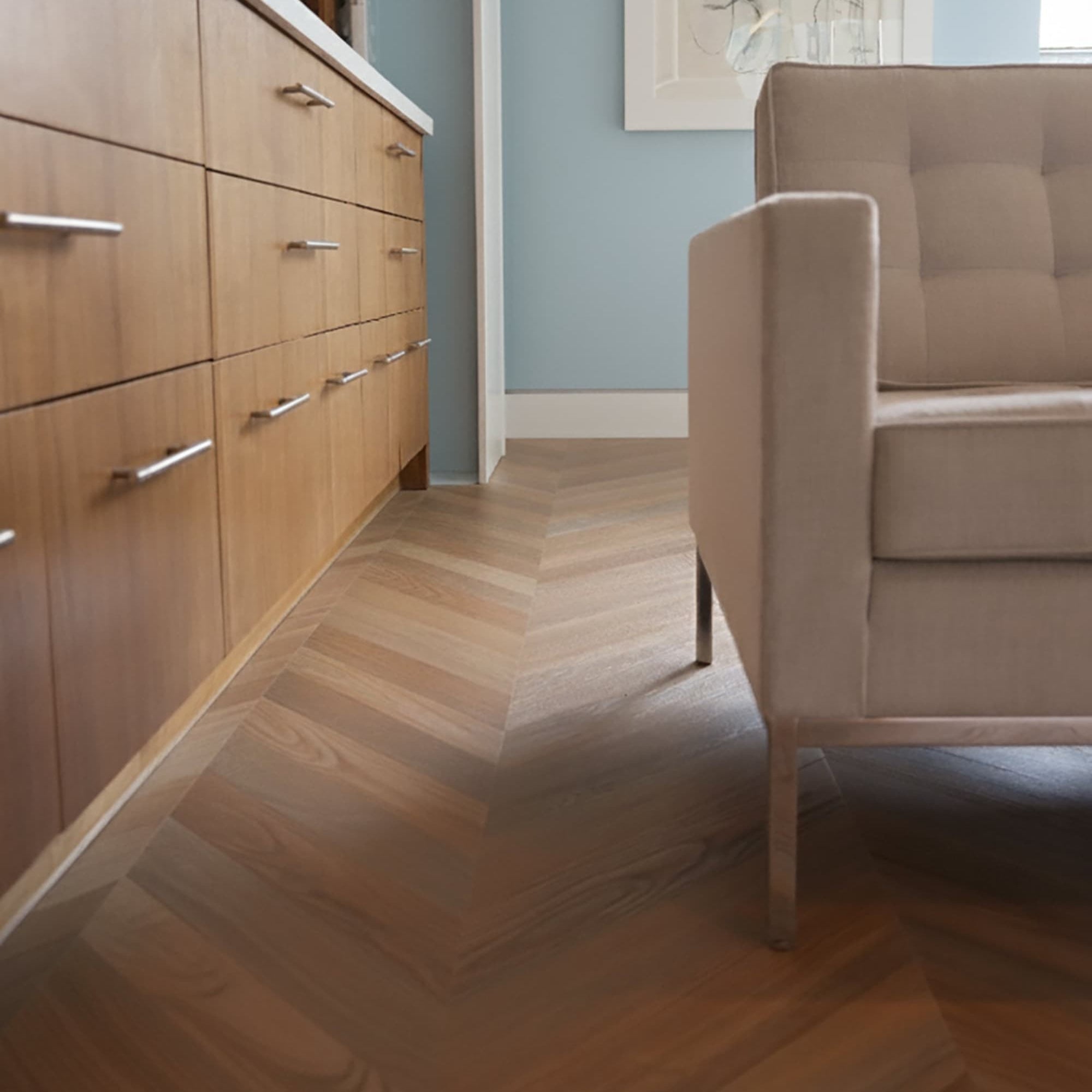 Chevron flooring with a white couch and row of cabinet drawers in a blue room