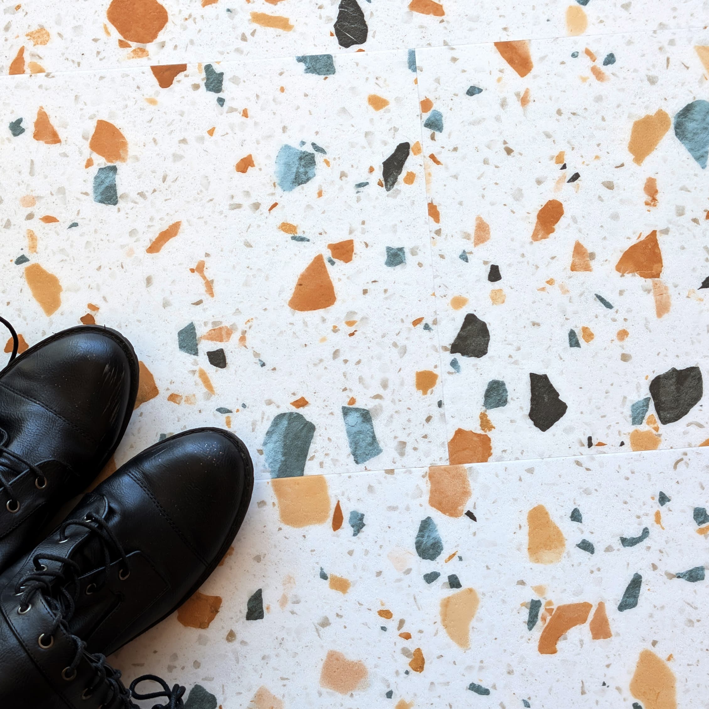 Black shoes on Allure terrazzo tile floor with multicolored chips.