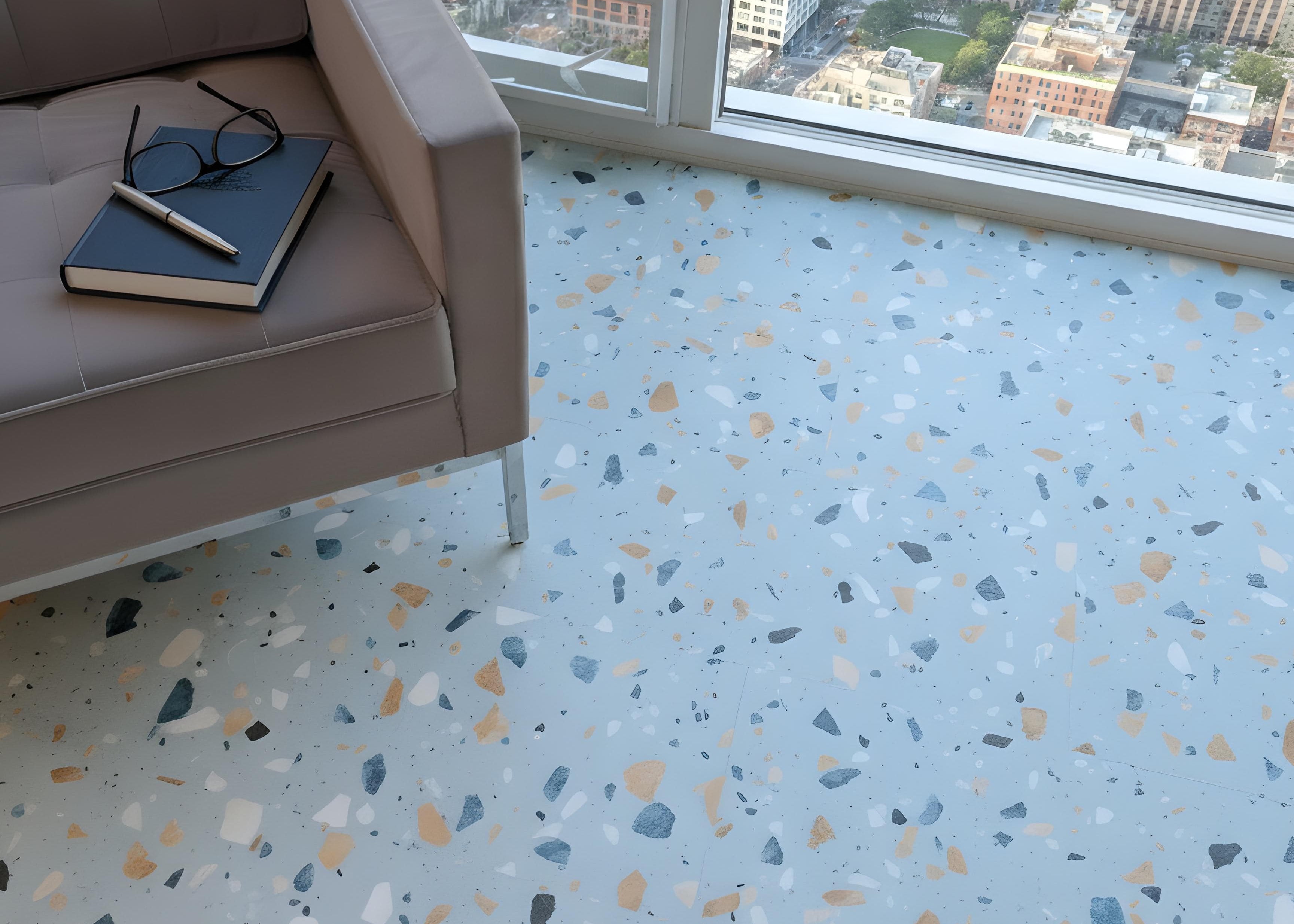 Allure Ultima Blue Agave Terrazzo tile flooring with city scape and gray modern chair, book and glasses.