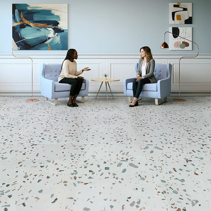 Two women sitting in a modern office with a terrazzo floor.