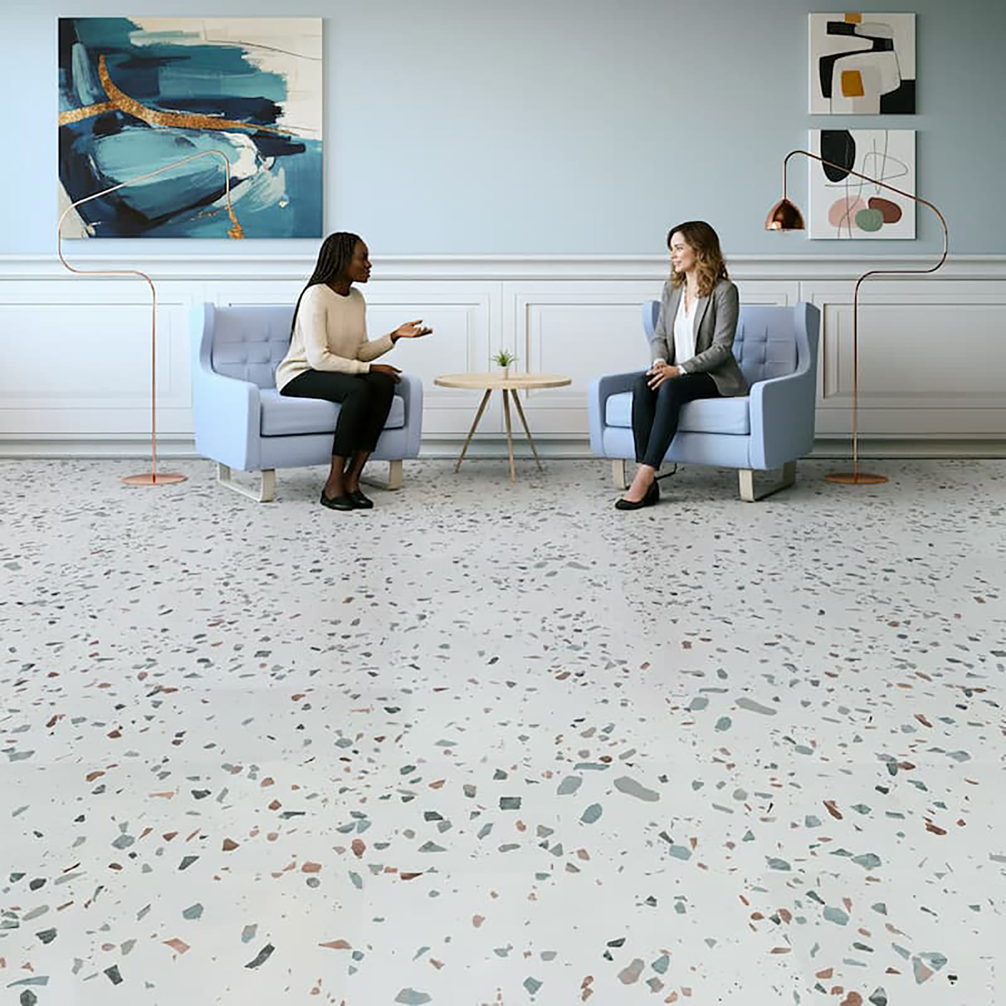 Two women sitting in a modern office with a terrazzo floor.