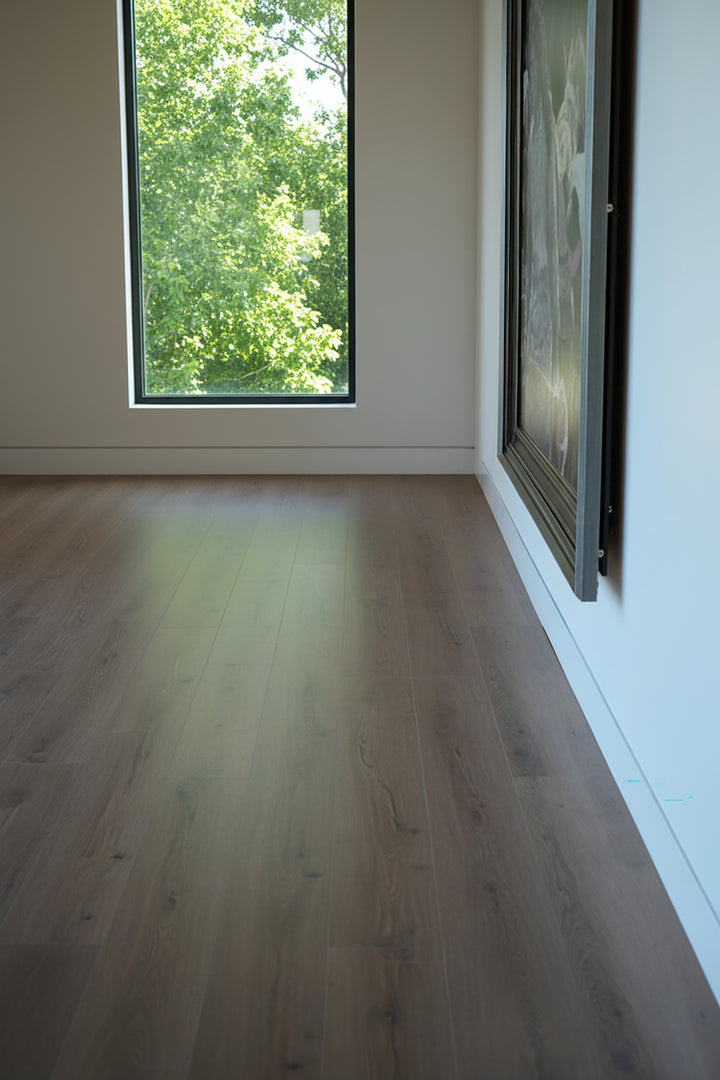 Empty room with Allure vanilla latte oak LVP floor and large window showing greenery outside