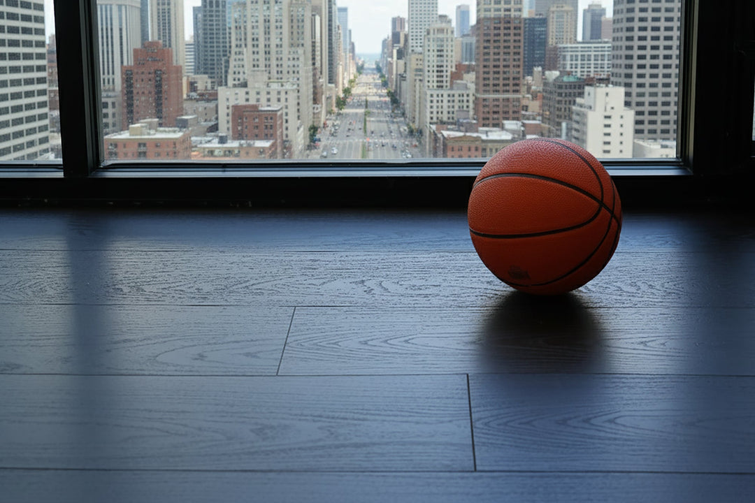 Basketball on a dark wood-look lvp floor with a cityscape view through large windows.