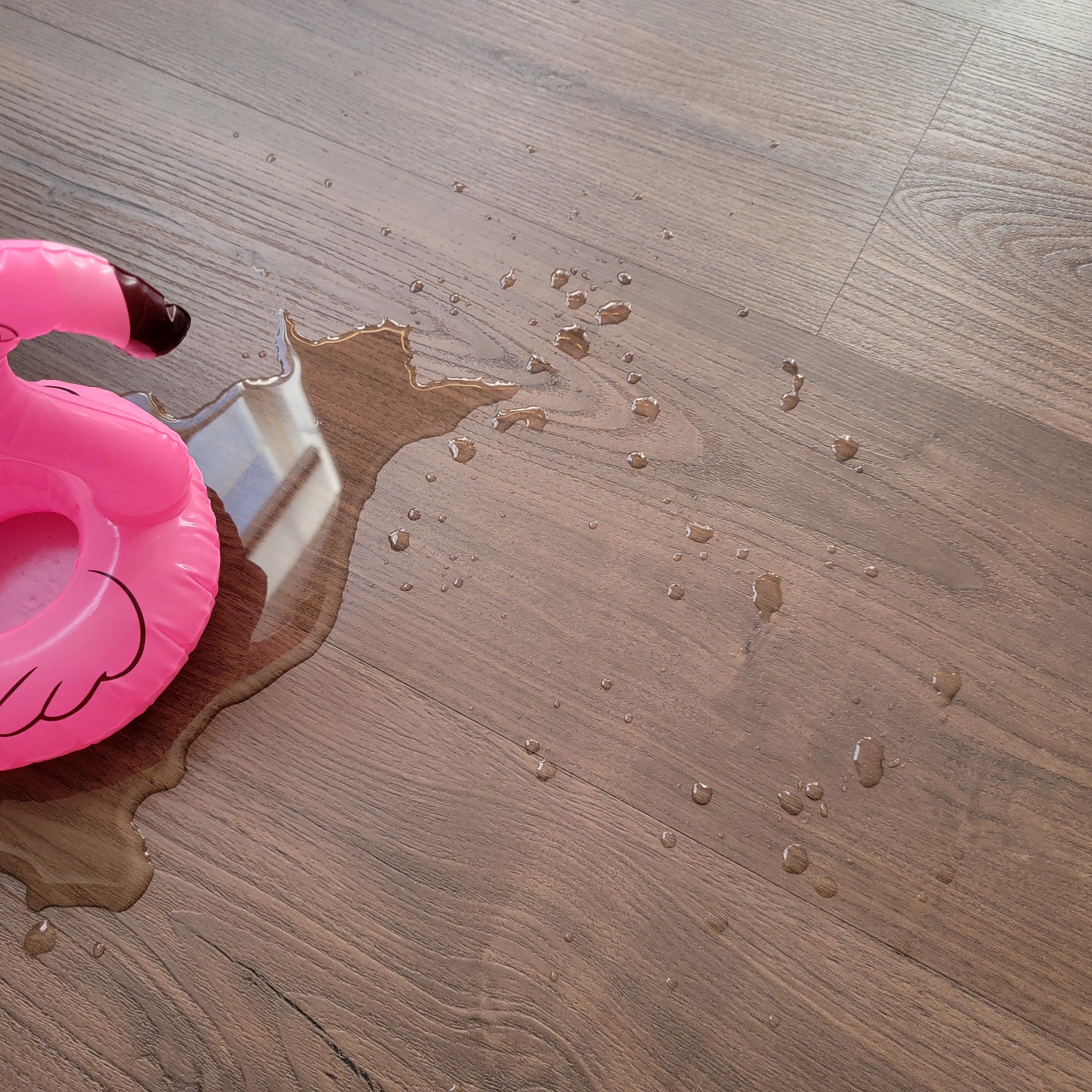 Dark brown vinyl plank flooring with Flamingo Inflatable and a puddle of water
