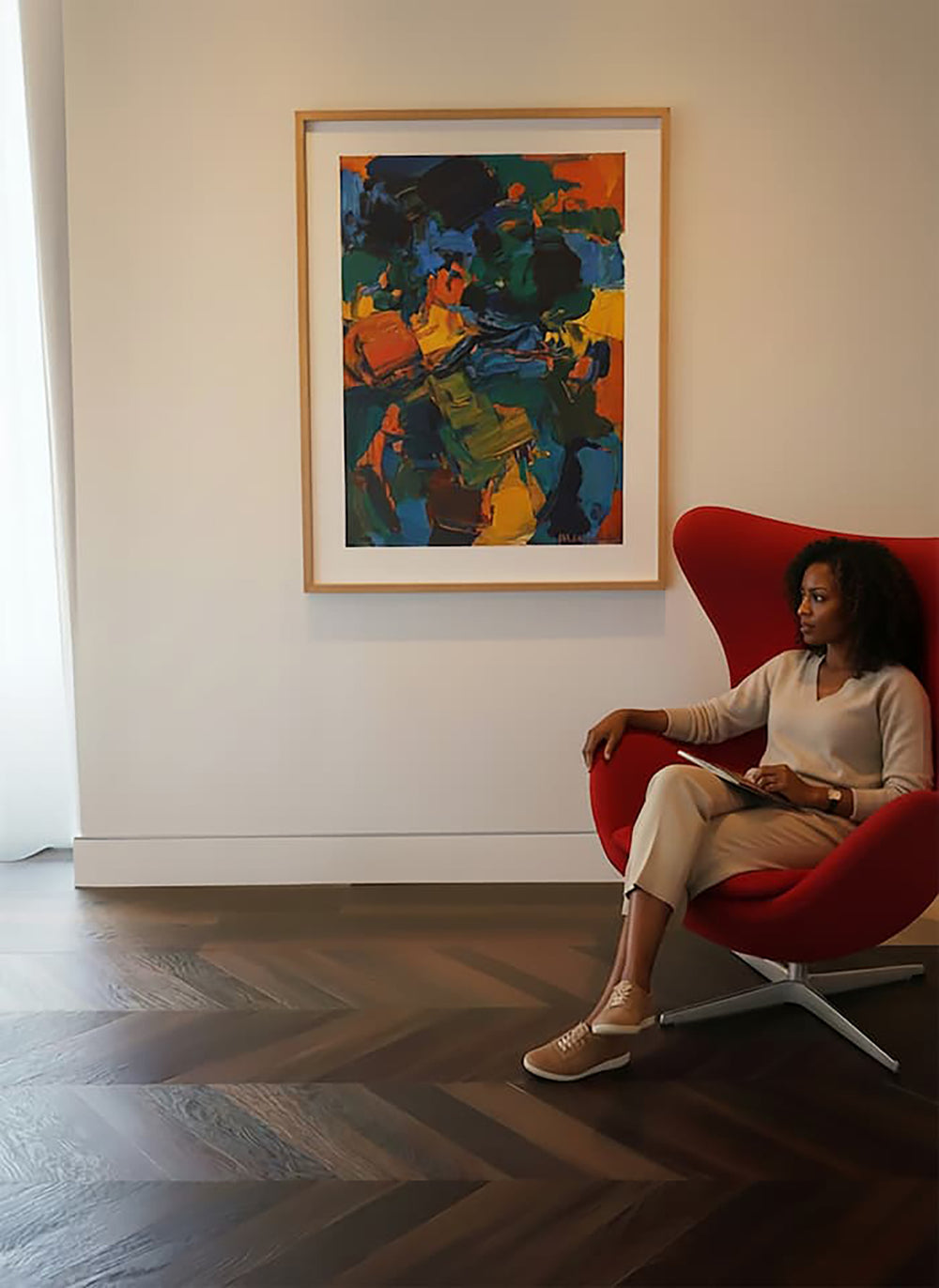 Woman sitting in red MCM chair with Allure chevron flooring and an abstract painting on the wall