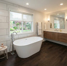 Modern bathroom with freestanding bathtub, wooden vanity, large window, and Allure dark brown vinyl plank flooring