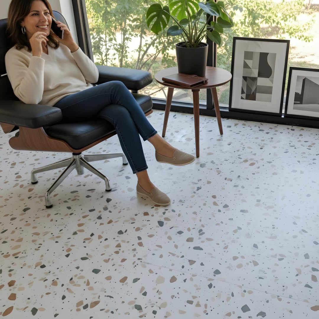 Woman sitting in a chair on an Allure terrazzo tile floor with a modern interior design.