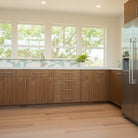 Modern kitchen with wooden cabinets, stainless steel refrigerator, large window and Allure LVP flooring