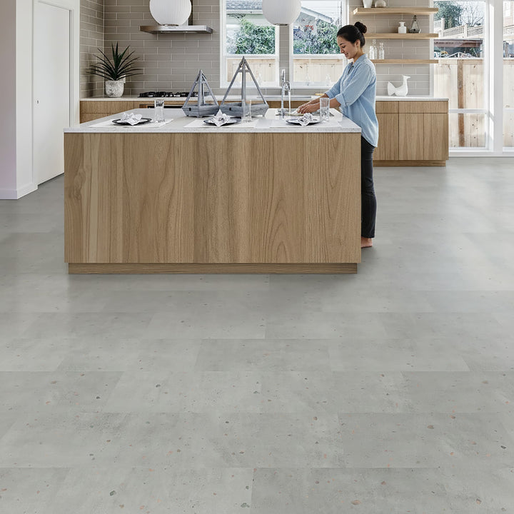Woman using a sink in her modern kitchen with Allure terrazzo tile flooring
