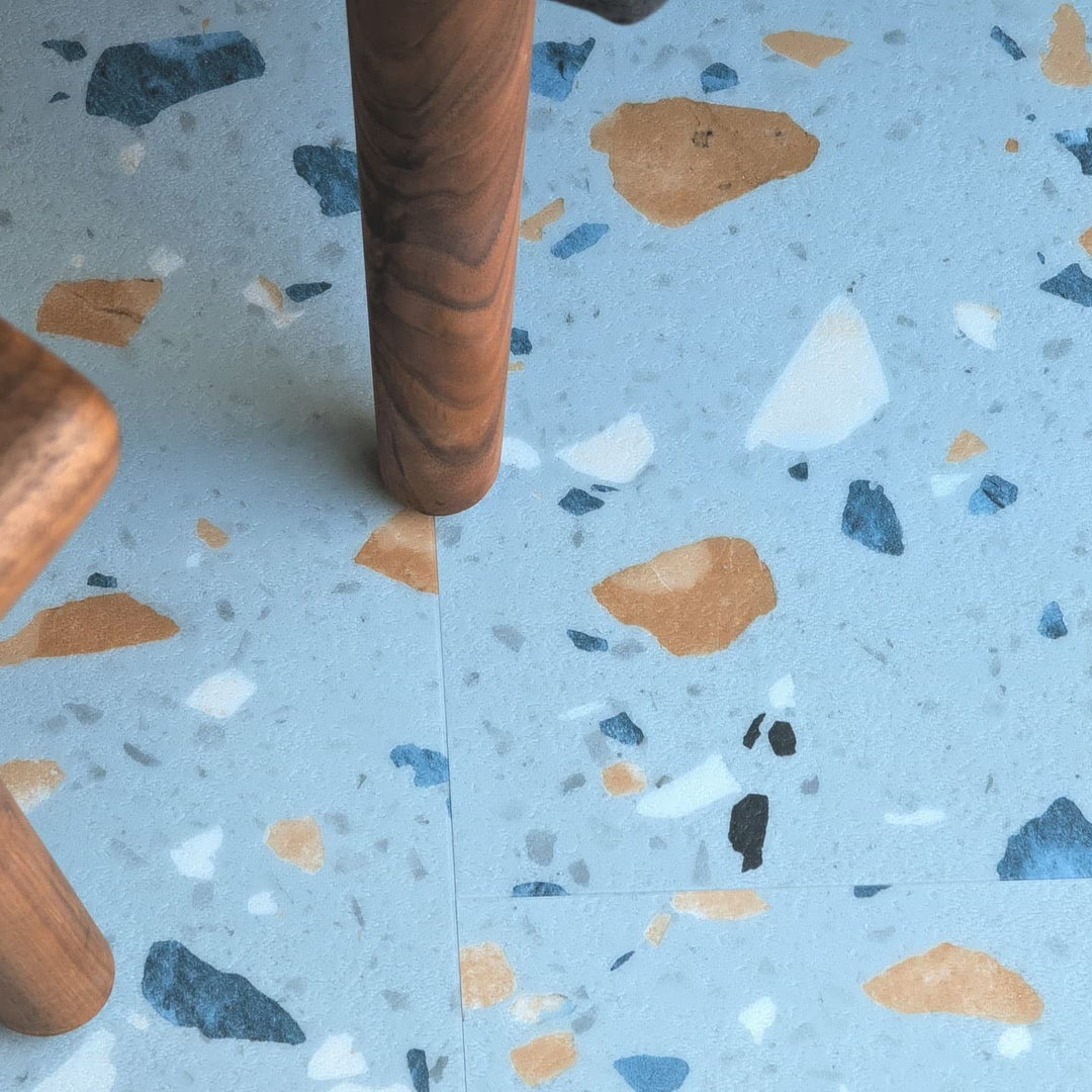 Close up of Allure Blue Agave Terrazzo LVT with furniture leg visible.