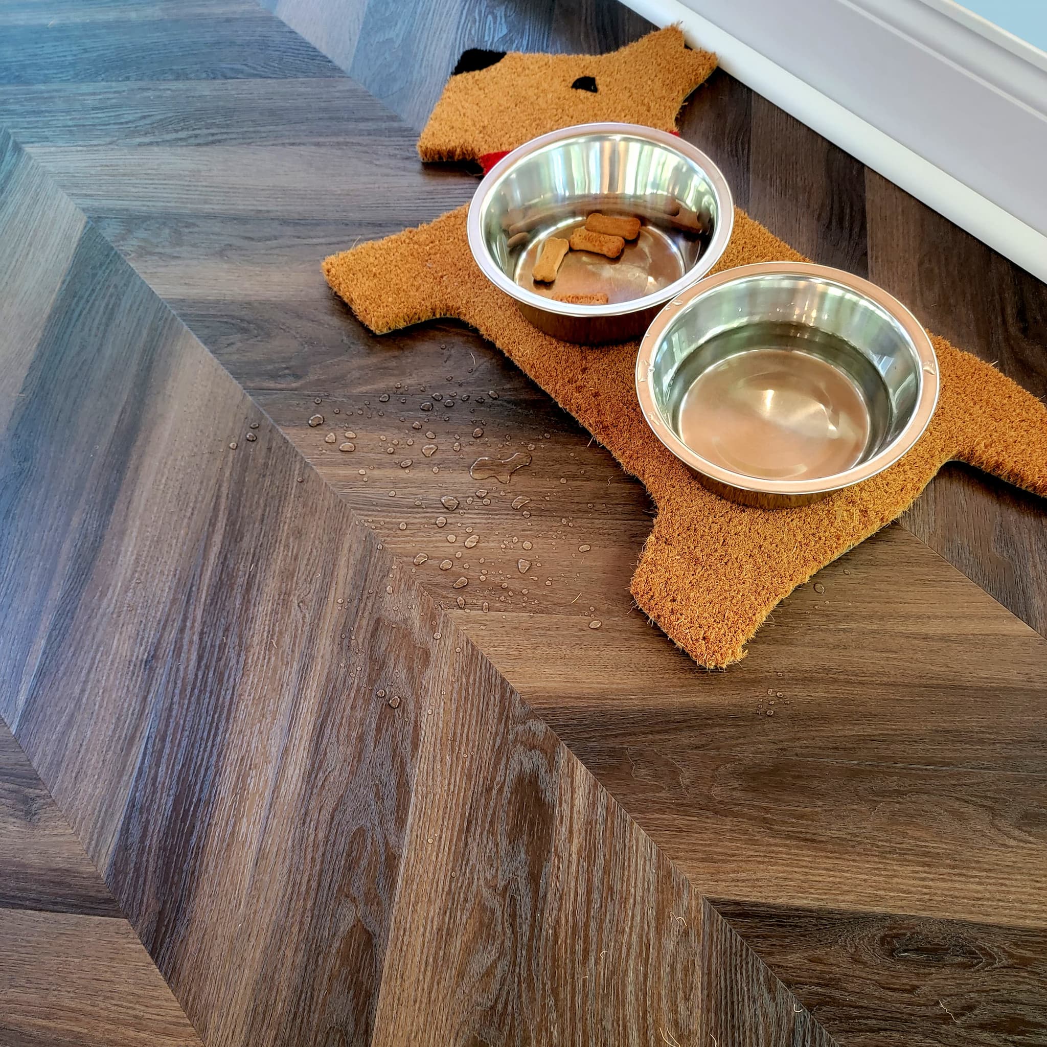 Dog mat with bowls on a dark wood look chevron luxury vinyl flooring