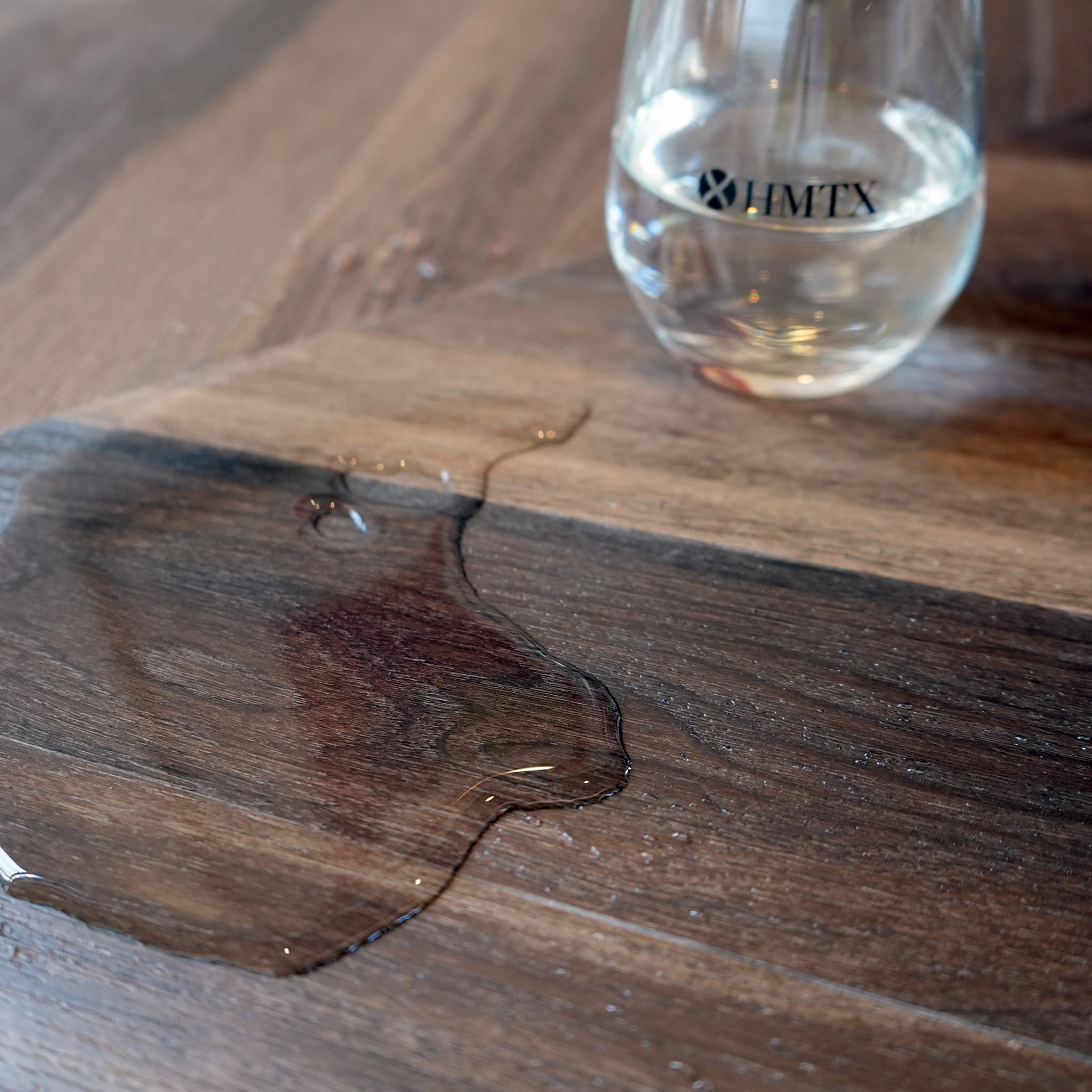 spilled water on Allure chevron flooring with glass half full in the background