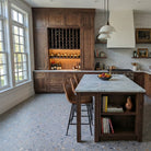 Modern kitchen with wooden cabinets, marble island, wine rack, and Allure Peach Pebble terrazzo LVT flooring