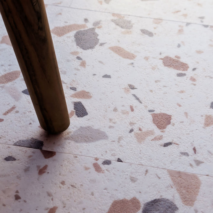 Close up of Allure Ultima Blush vinyl tile flooring with brown chair leg