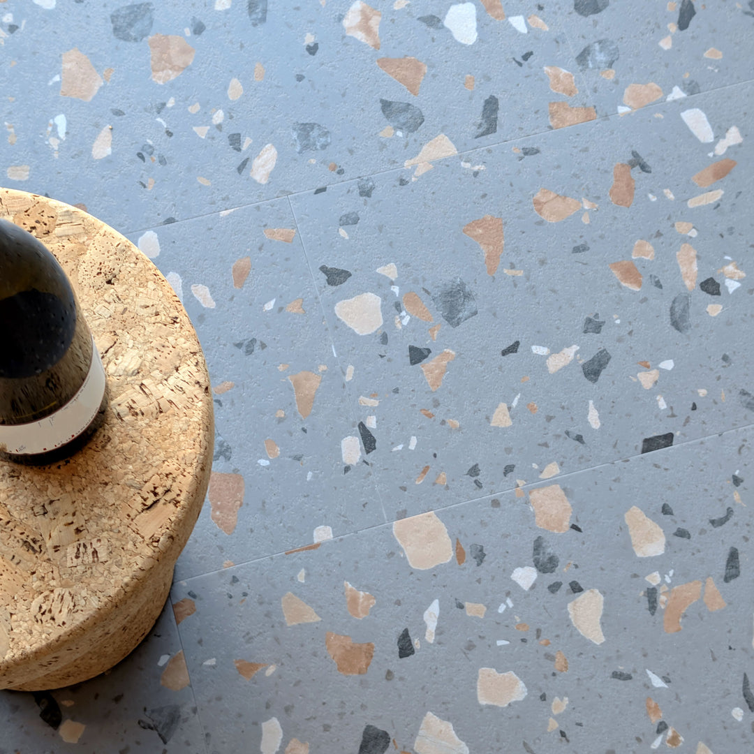 Close up of Allure  Ultima Peach Pebble LVT flooring with MCM cork side table and wine bottle