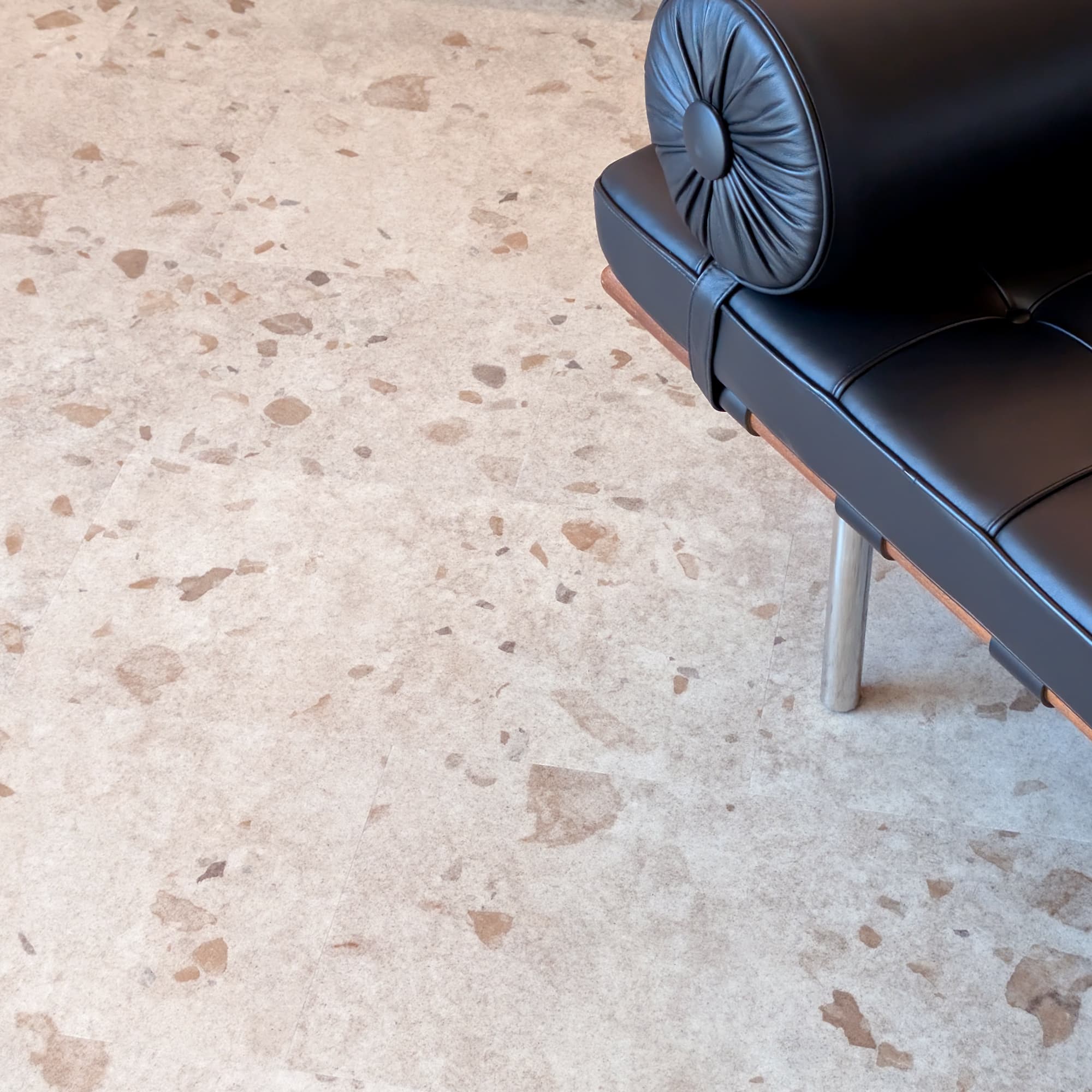 Black leather MCM bench on a terrazzo vinyl tile floor