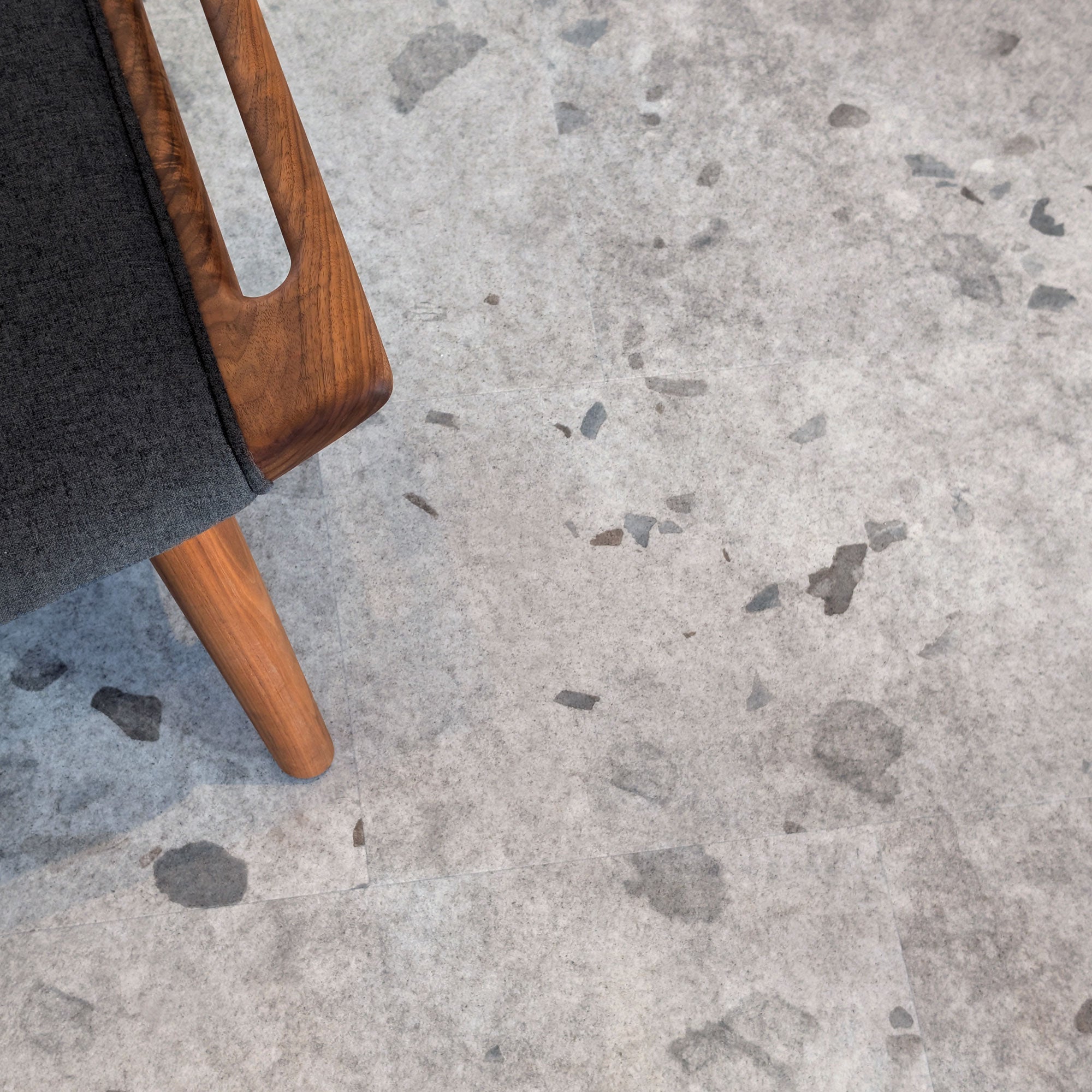 Close up of Galaway Grey terrazzo MCM flooring with wooden chair