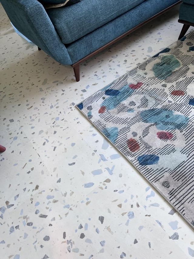 Colorful rug on a ultima parfait terrazzo floor with a blue sofa in the background