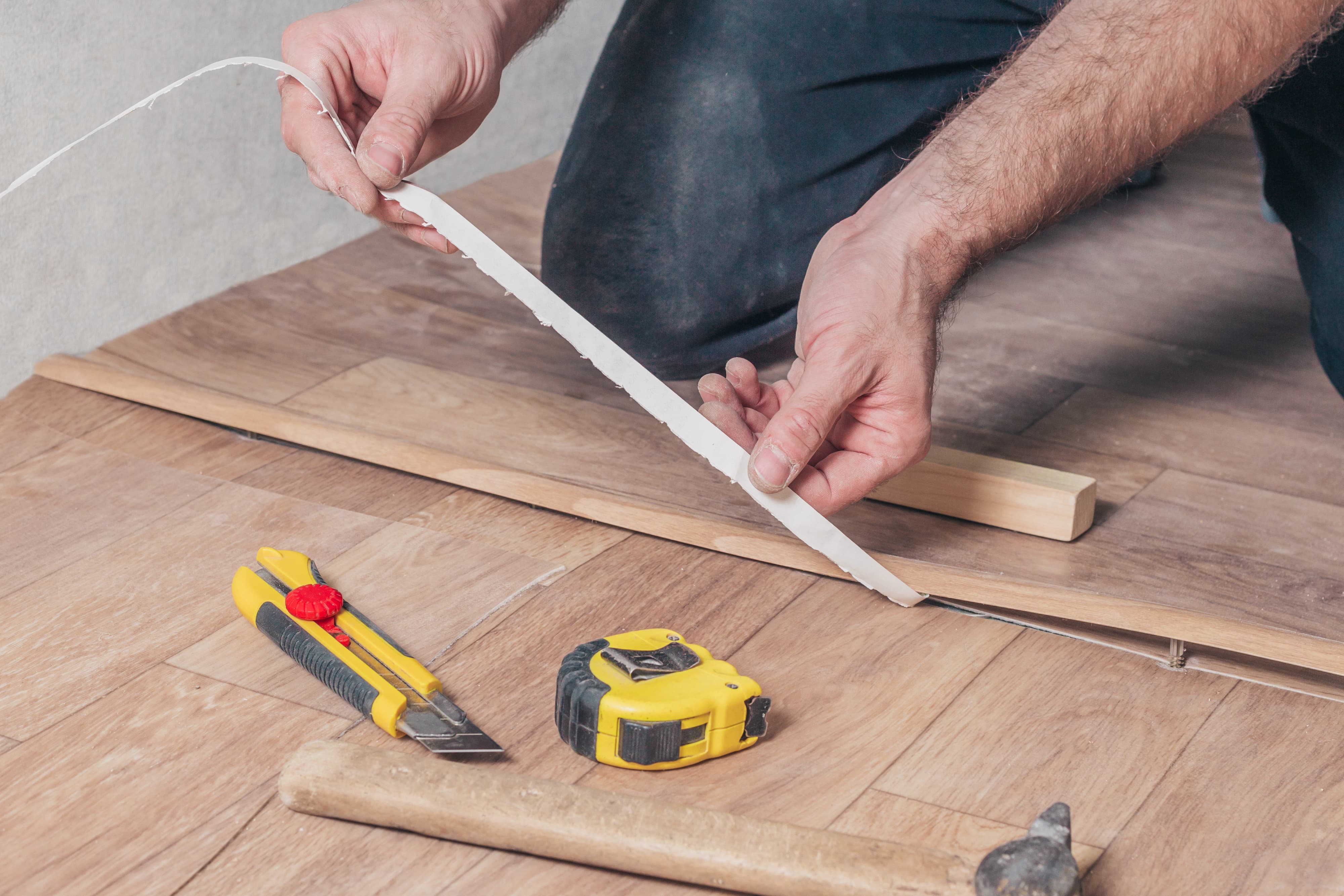 person installing t-molding between two vinyl flooring pieces