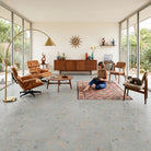 Modern living room with a woman sitting on a rug, surrounded by furniture and decor.
