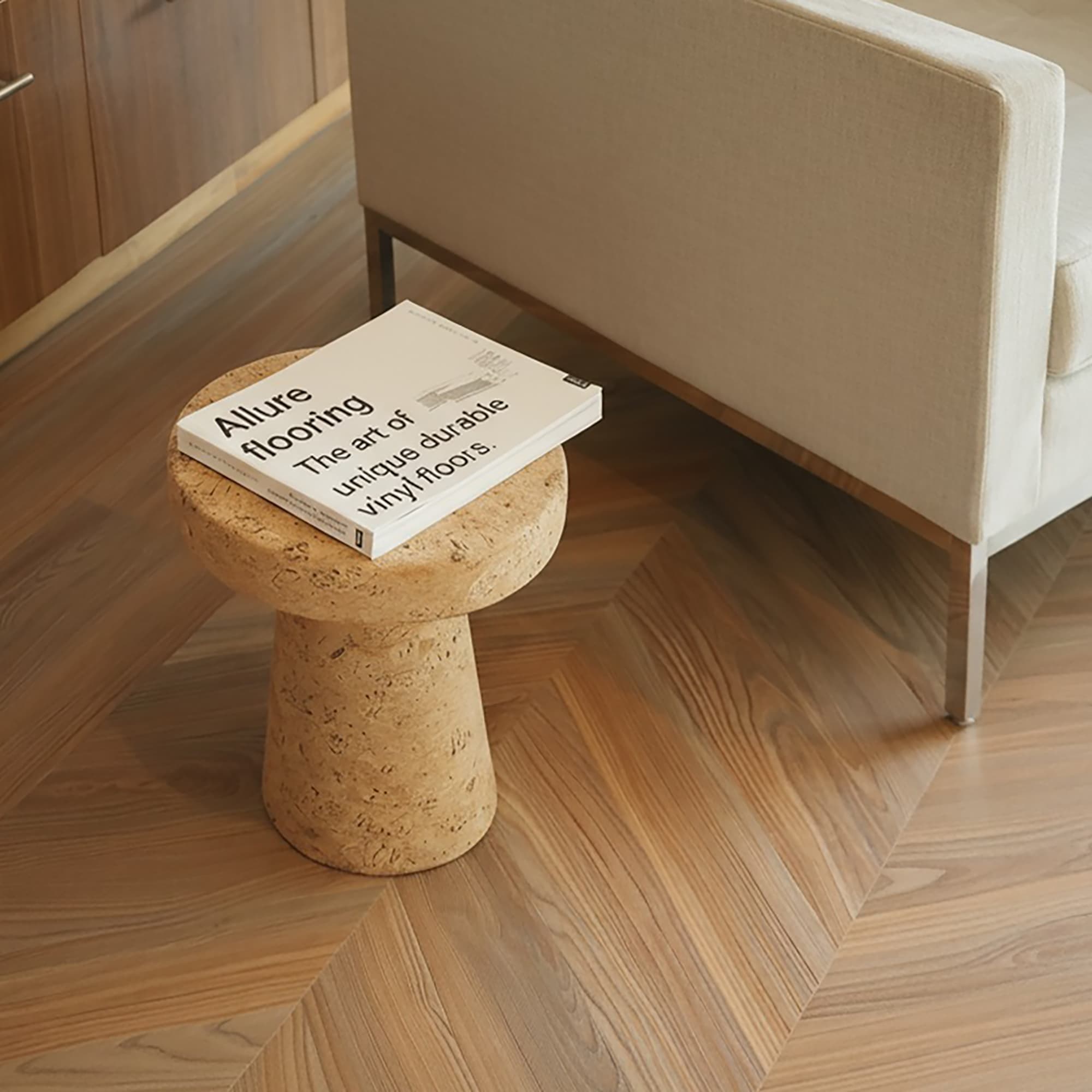 Allure chevron flooring with side table, book and white modern chair.