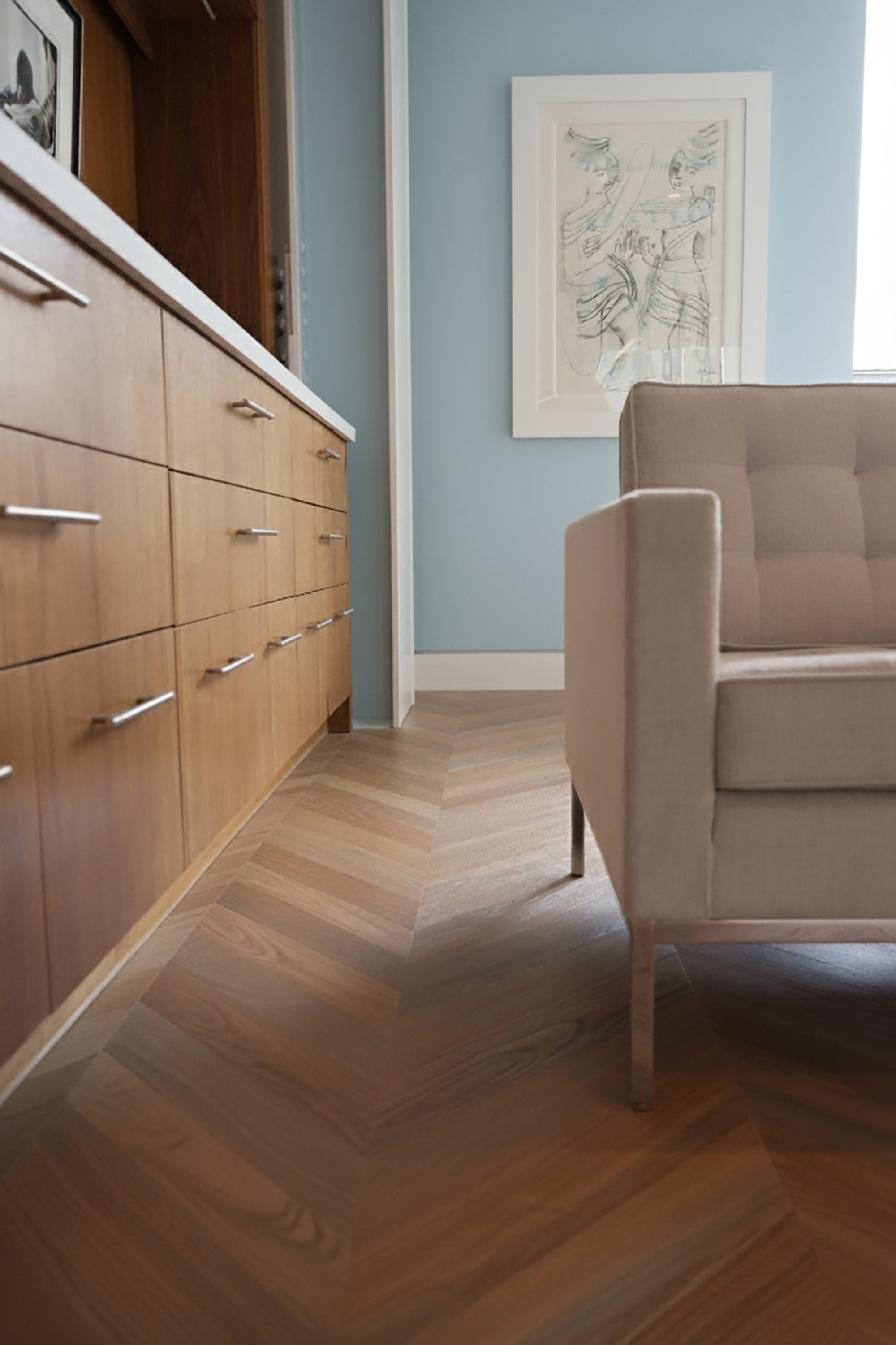 Chevron flooring with a white couch and row of cabinet drawers in a blue room