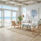 Living room with a view of the ocean, featuring a white sofa, wicker chairs, and a coffee table.