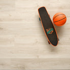 Allure luxury vinyl plank flooring in Soft Oak Sand installed floor view from above with skateboard and basketball