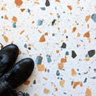Black shoes on Allure terrazzo tile floor with multicolored chips.