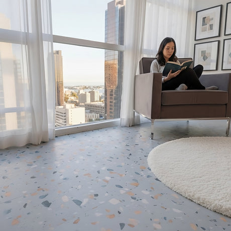 Woman sitting in modern chair reading in condo with Blue Agave Terrazzo vinyl tiles by Allure