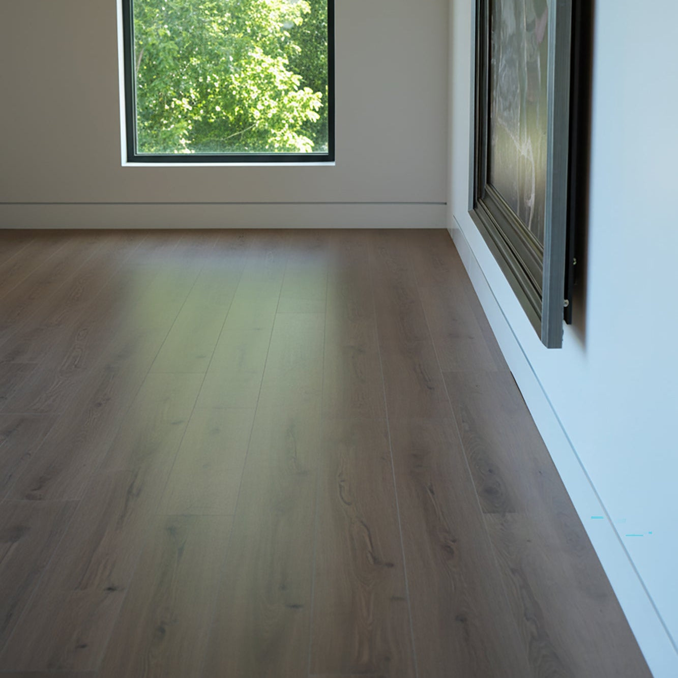 Empty room with Allure vanilla latte oak LVP floor and large window showing greenery outside