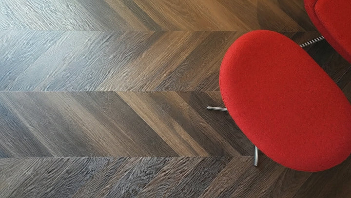 Dogs walking around on dark chevron floors circling a modern red chair